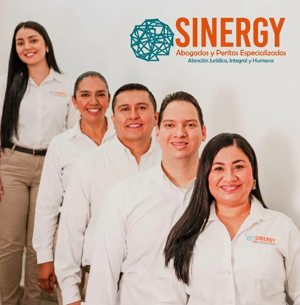 El equipo de Sinergy Abogados y Peritos Especializados, seis personas en camisa blanca frente al logo de la firma.